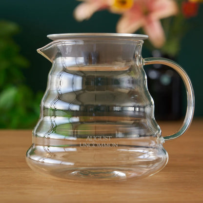 Clear glass two-cup teapot with curved handle and spout, empty interior.