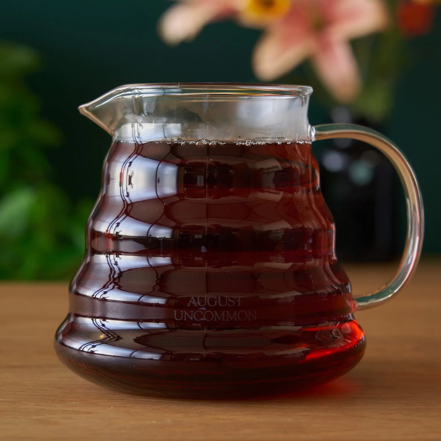 Glass two-cup teapot with amber tea, clear handle and angled spout.