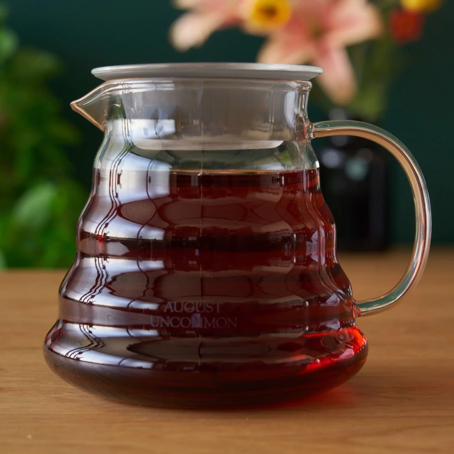 Glass two-cup teapot with amber tea inside, clear handle and spout.