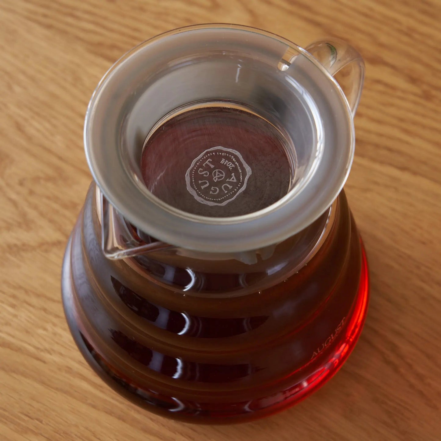Two-cup glass teapot top view with amber tea and filter disc.