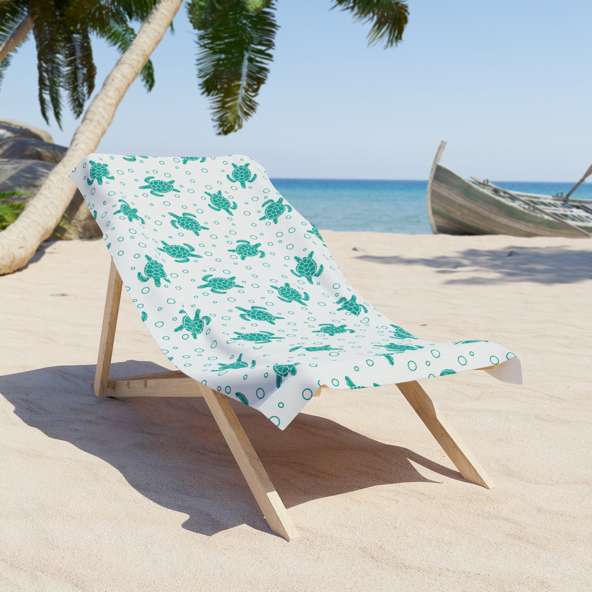 Beach towel draped on lounge, teal sea turtle pattern on white fabric
