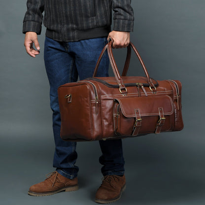 Brown leather weekender duffel being carried with dual handles and adjustable crossbody strap