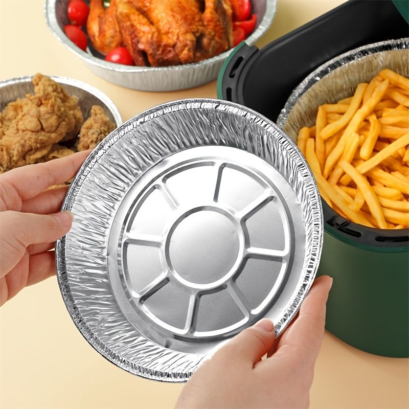 Round aluminum foil liner pan with circular base insert, held in hands with fries nearby