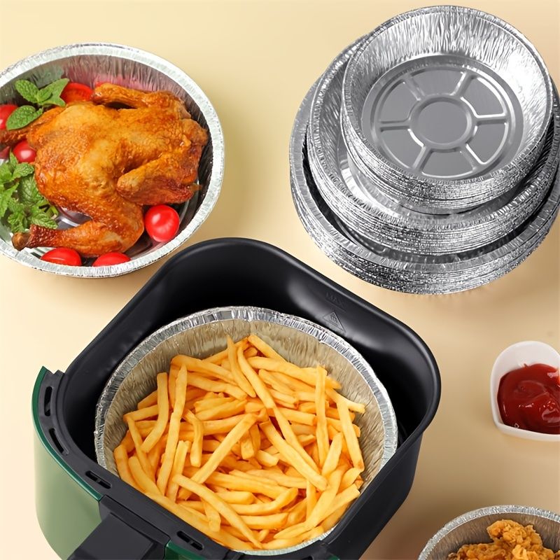 Stack of round aluminum foil liners near air fryer basket, one filled with fries