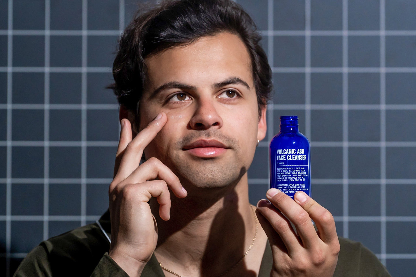 Man holding a blue face cleanser bottle with black cap