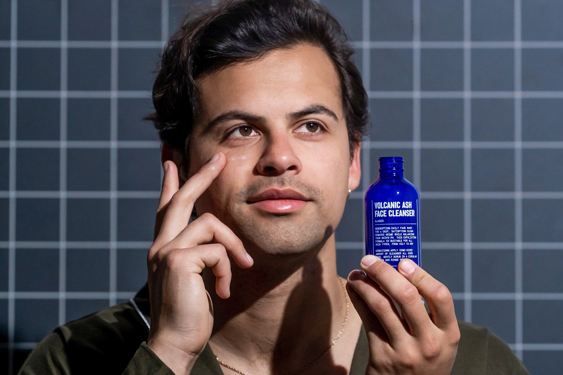 Man holding a blue face cleanser bottle with black cap