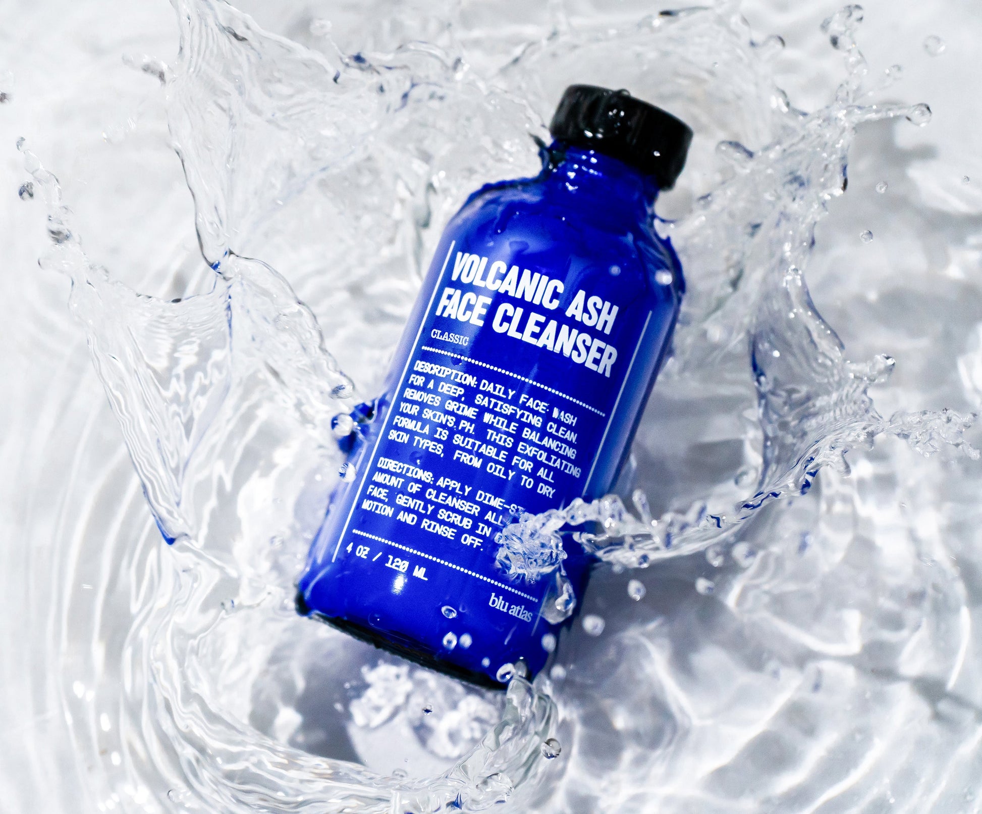 Blue face cleanser bottle with black cap in water splash