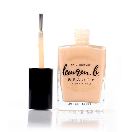 Nail base coat bottle with nude peach polish and brush applicator.