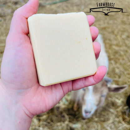 Unscented soap bar, pale cream rectangular block held in hand