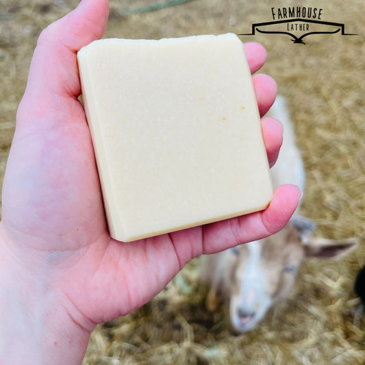Unscented soap bar, pale cream rectangular block held in hand