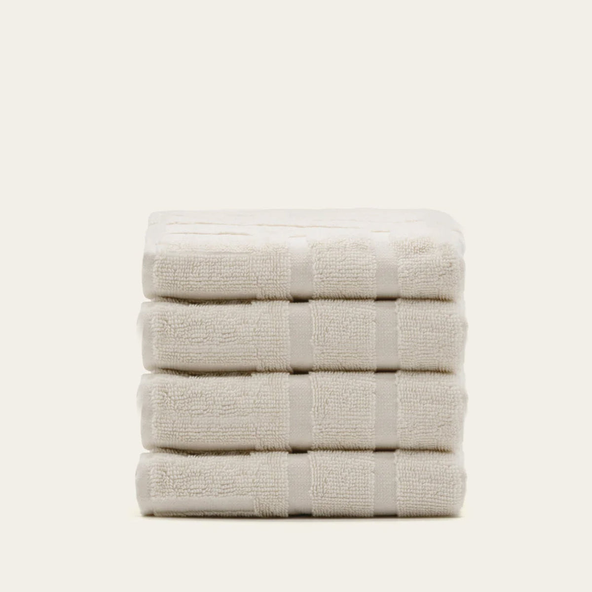 Stacked ecru cotton towels with textured stripes across the folded layers