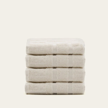 Stacked ecru cotton towels with textured stripes across the folded layers
