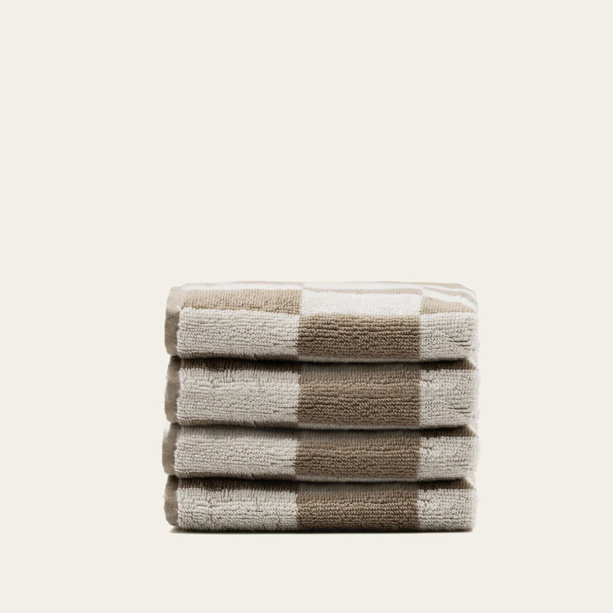 Folded striped cotton towels stack in tan and ecru with plaid band accents.