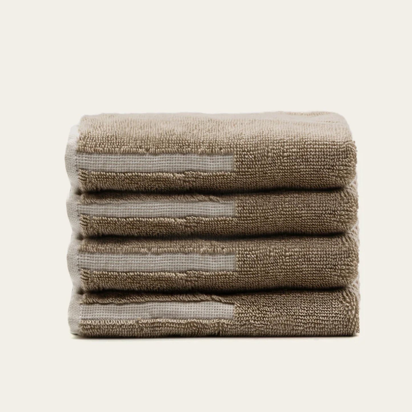 Three folded tan cotton towels with ecru accent bands