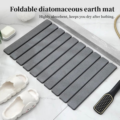 Foldable dark gray diatomite bath mat with ribbed strips, neatly folded.