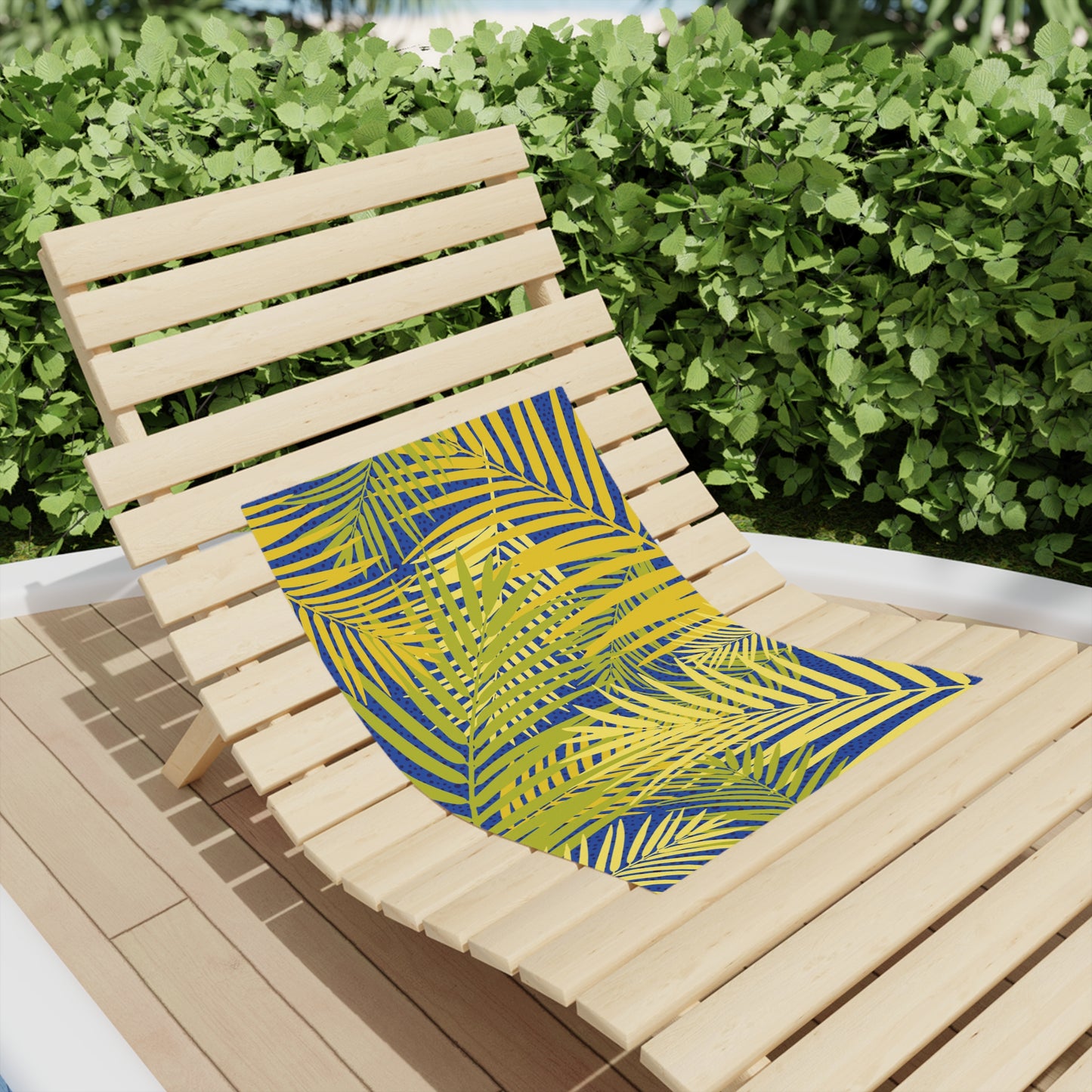 Beach towel with yellow base and blue tropical palm leaves, draped