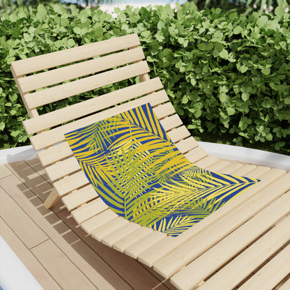 Beach towel with yellow base and blue tropical palm leaves, draped