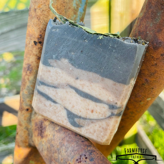Striped bar soap with blue and cream layers and a small green herb leaf on top