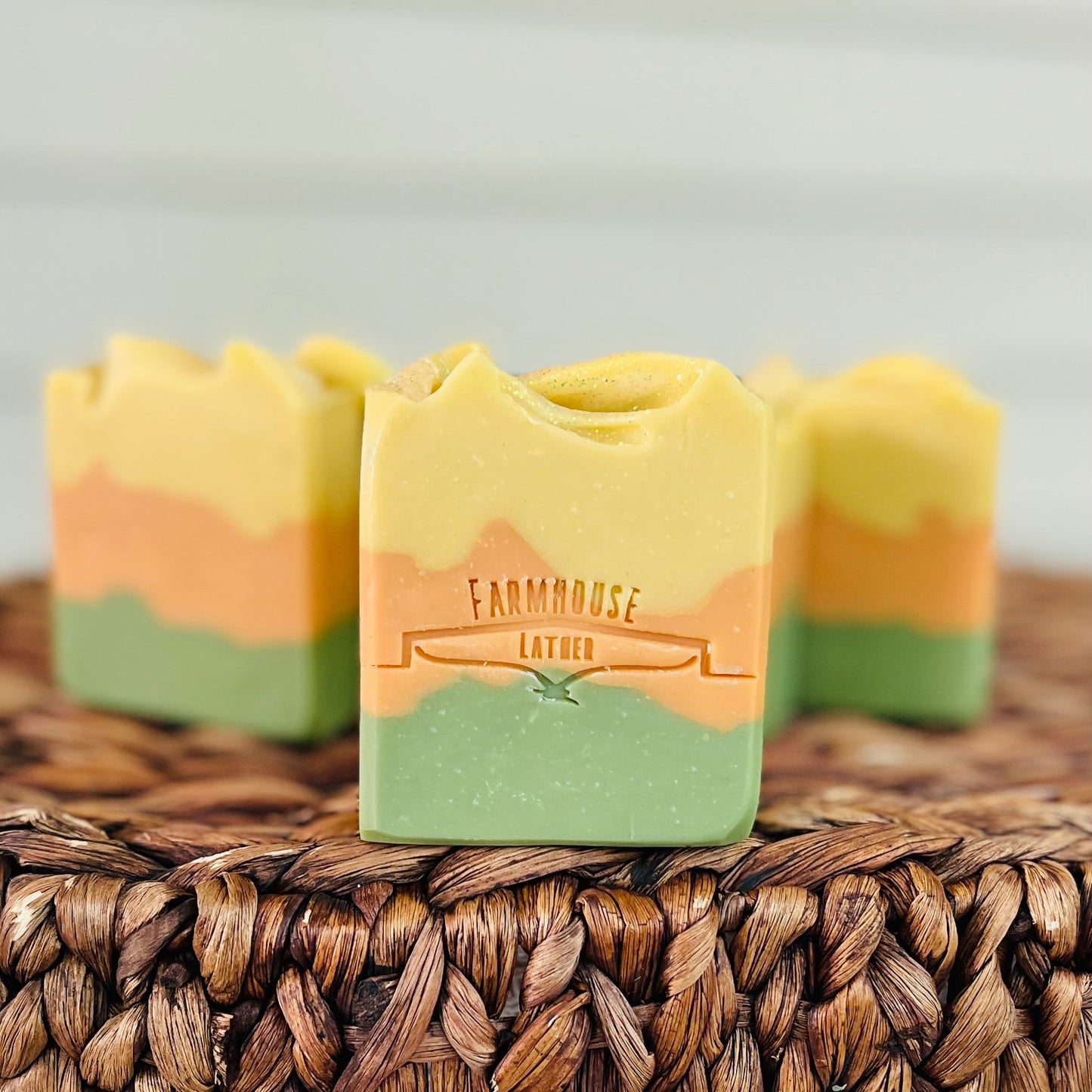 Three-layer soap bars in yellow, orange, and green with brand label