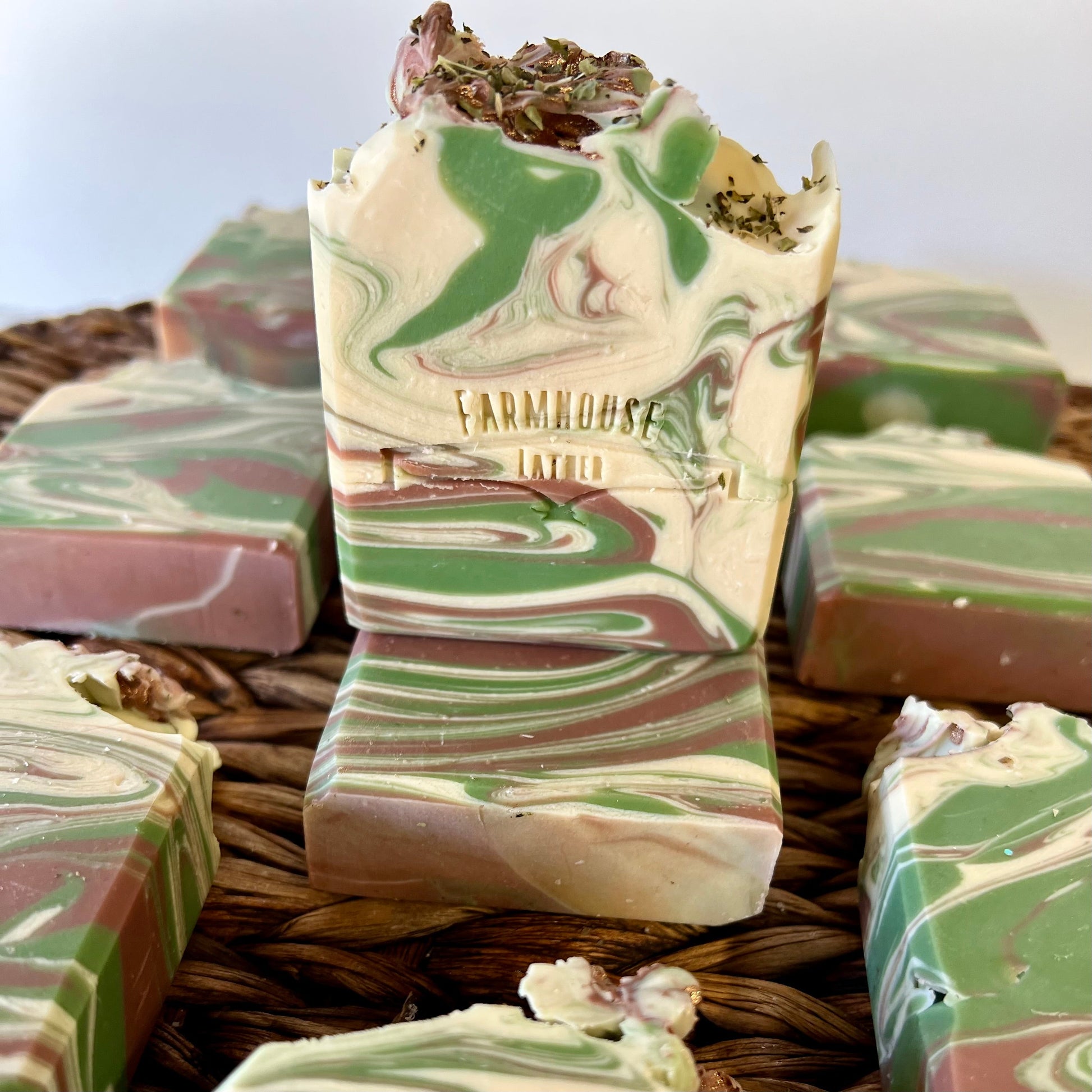 Marbled soap bar with green and cream swirls, with other bars behind