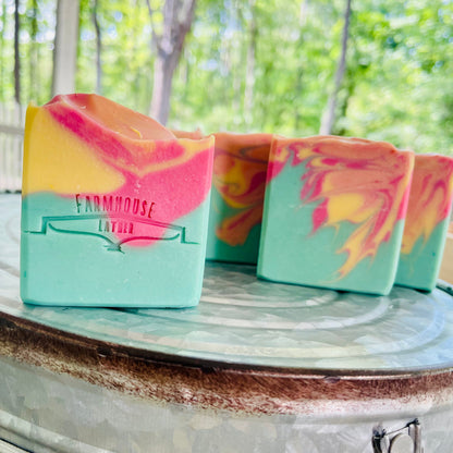 Marbled soap bars in teal, pink, and yellow with Farmhouse labels, side angle.
