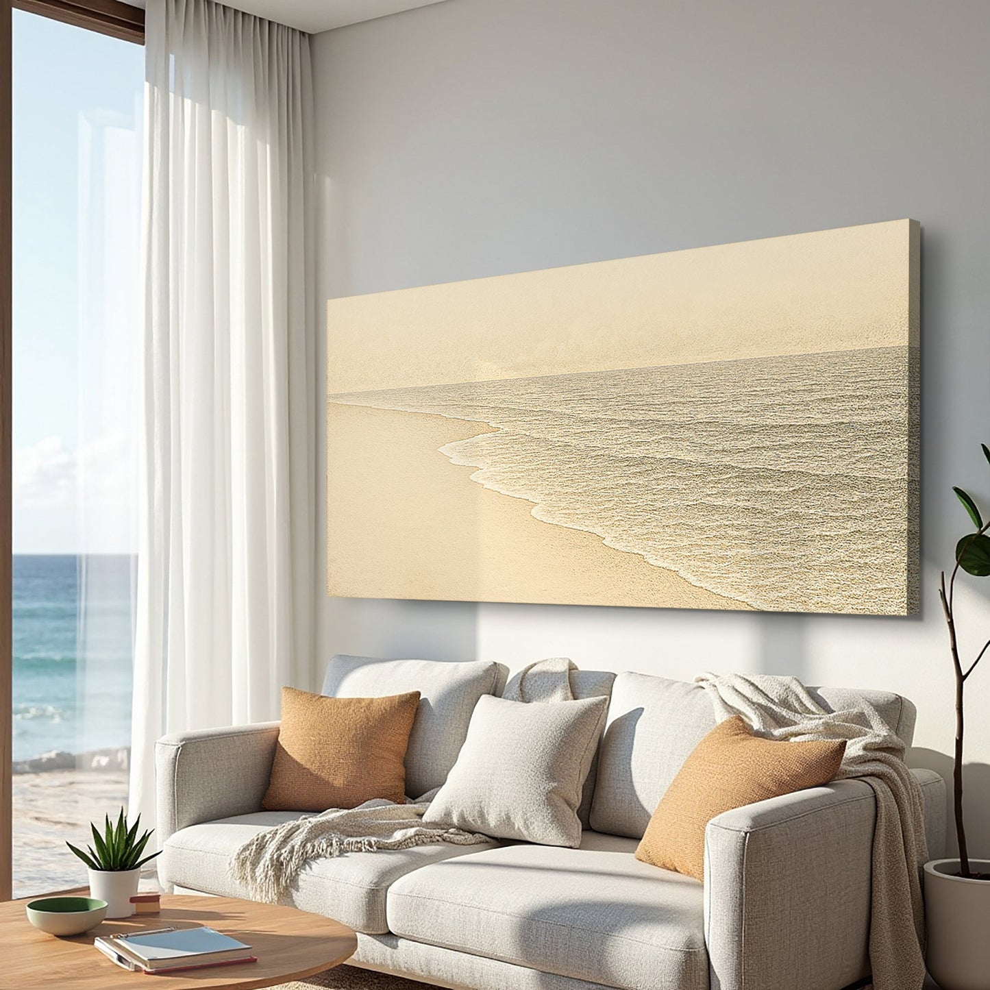 Coastal wall art canvas mounted above a sofa, with pale sand and textured gray shoreline