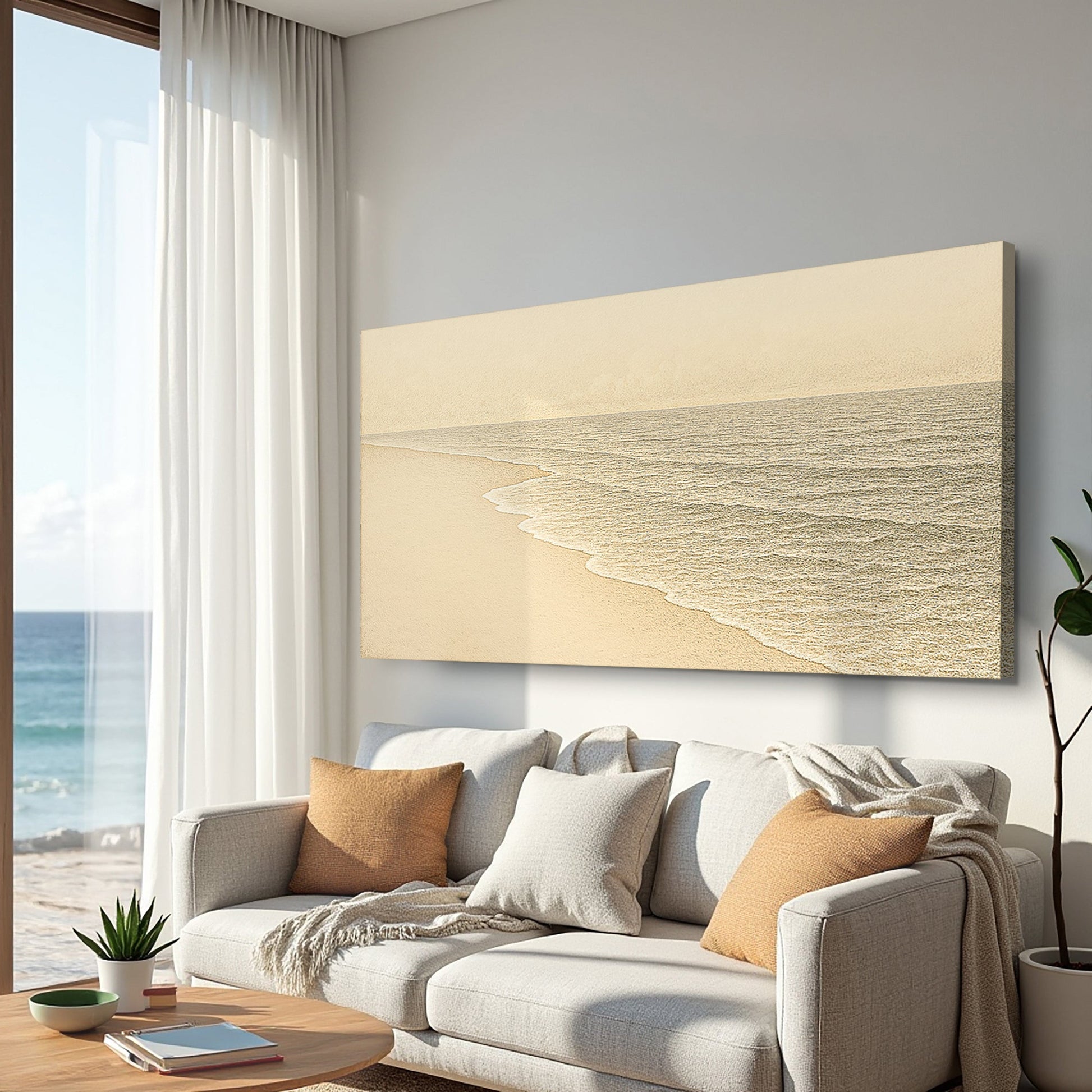 Coastal wall art canvas mounted above a sofa, with pale sand and textured gray shoreline