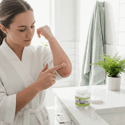 Nutrasporin ointment jar on bathroom counter as a woman applies ointment to a sore spot