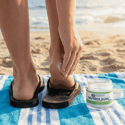 Skin balm application to feet, with small skin balm jar beside towel