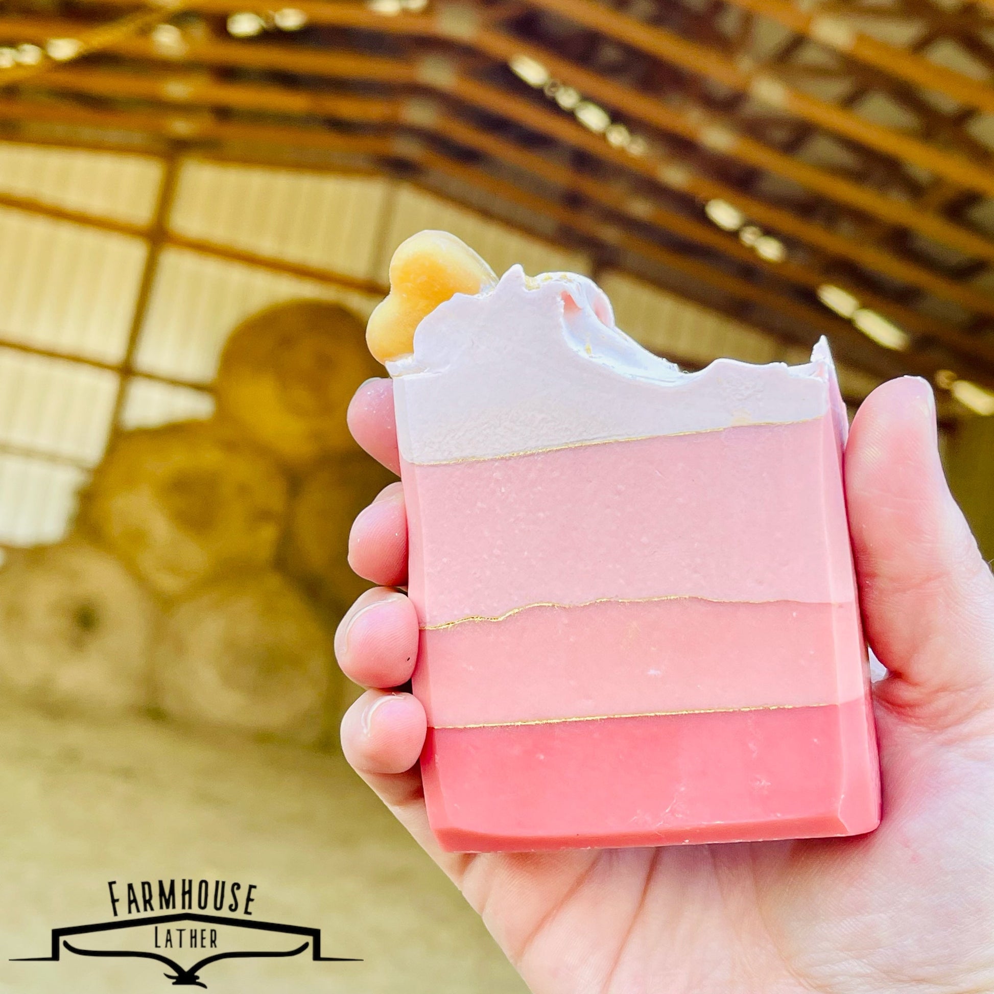 Layered pink and white soap bar with yellow accent at top, hand-held