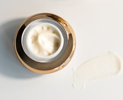 Under eye cream jar top view with thick white cream and gold rim.