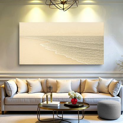 Coastal wall art canvas above a light sofa, featuring a pale beach and gray ocean