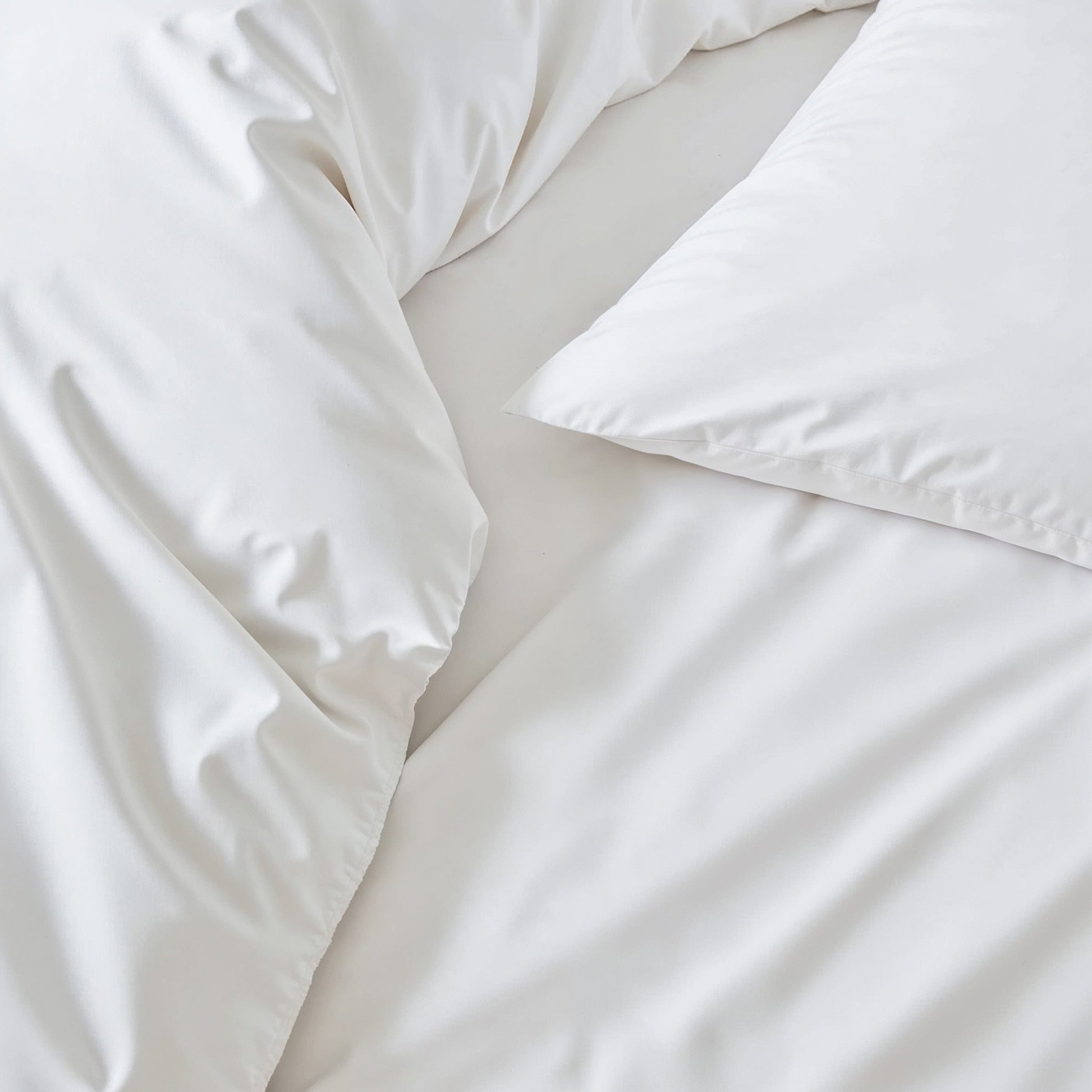 Sateen sheet set in white, close-up of smooth bedding folds