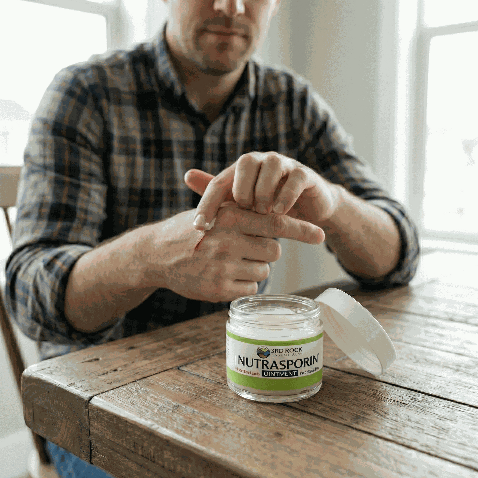 Nutrasporin ointment jar on wooden table while hands apply ointment to wrist