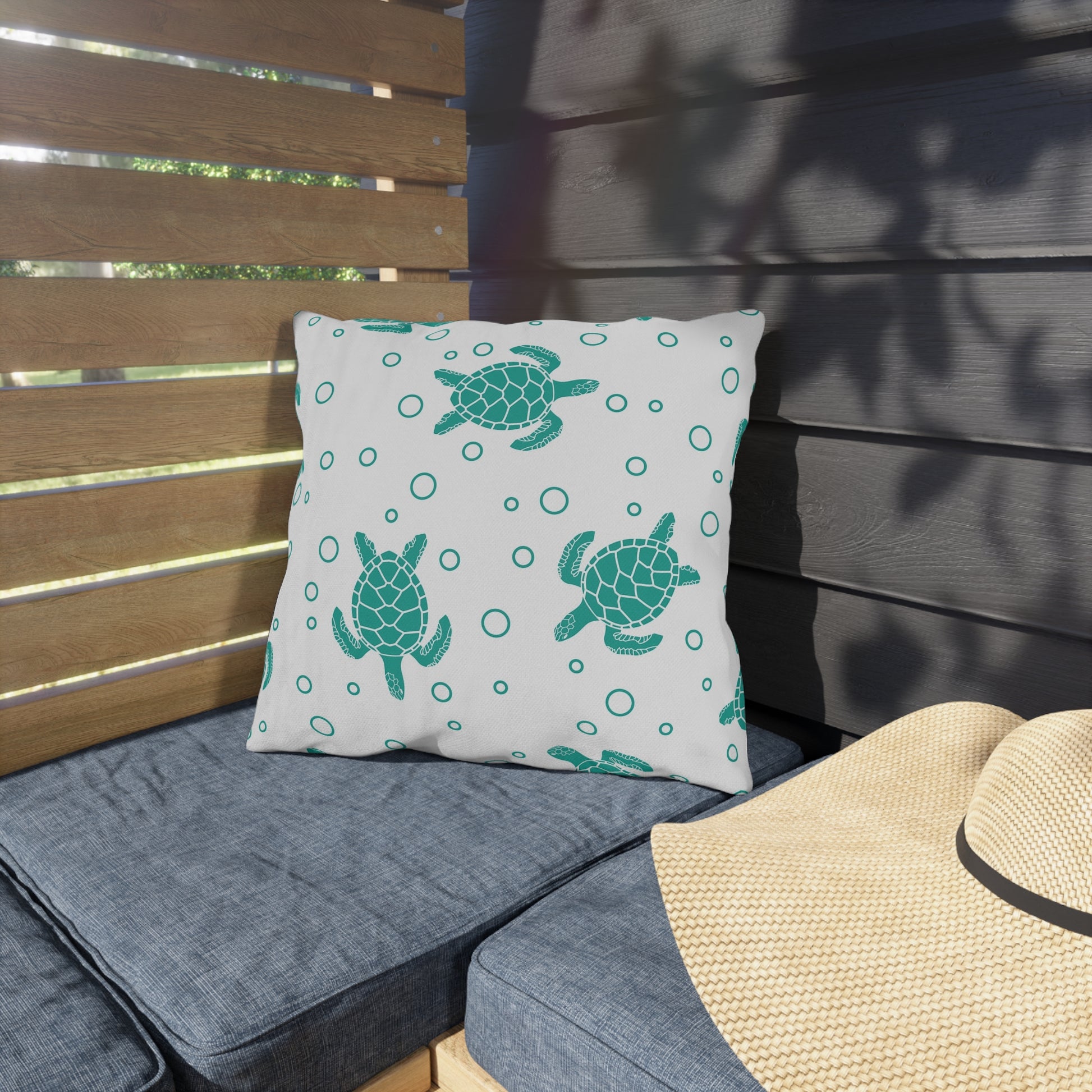 Square outdoor cushion pillow with teal sea turtle print and ring dots on white fabric.