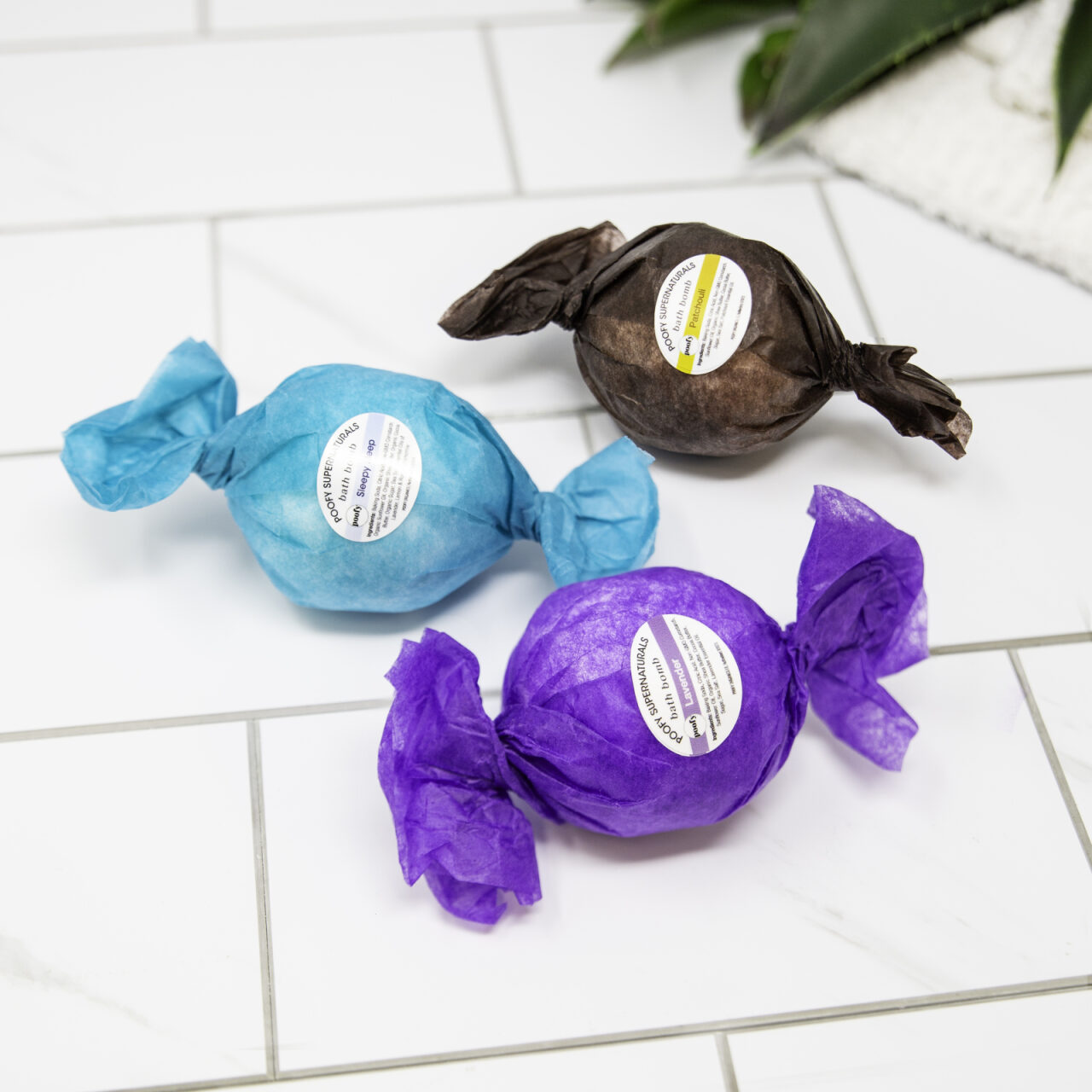 Bath bomb trio: blue, purple, and dark brown wrapped bombs with labels