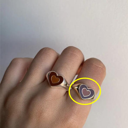 Heart enamel ring on finger with dark red center and gold-tone bezel