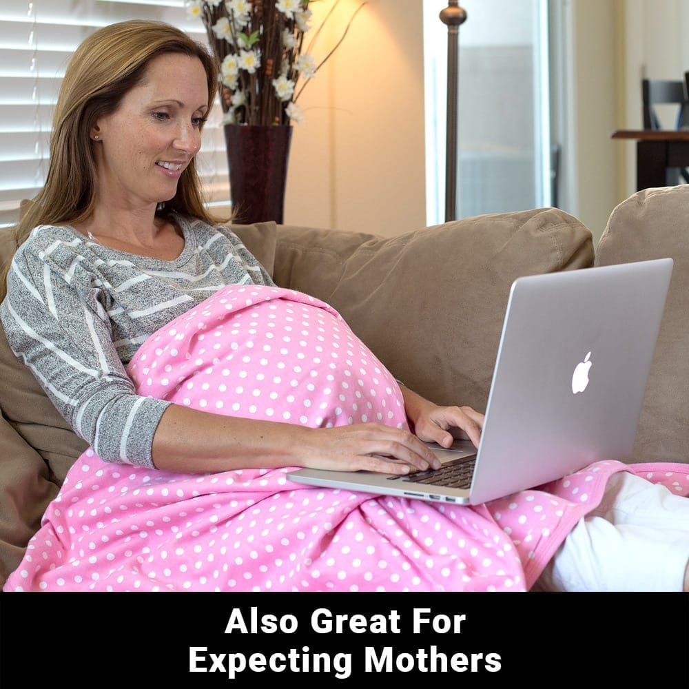 Pink baby blanket with white polka dots draped on a pregnant woman on a sofa