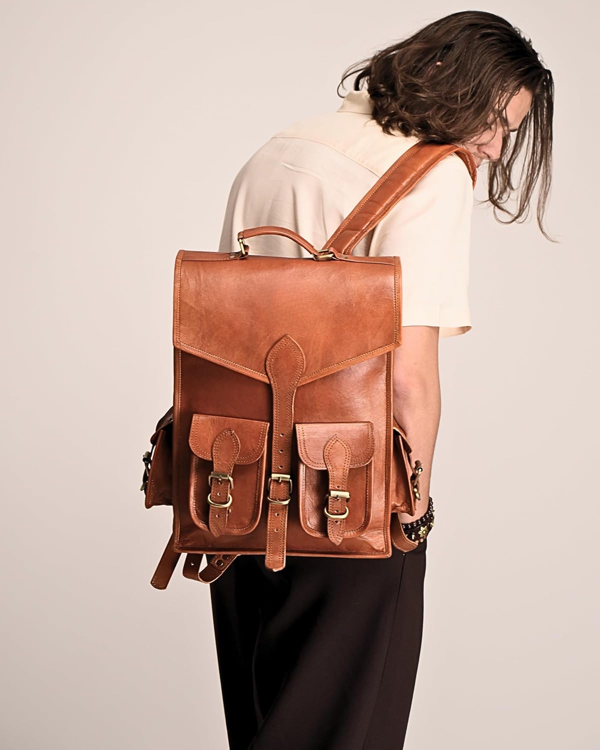 Brown leather backpack with rear panel and adjustable shoulder straps, shown from behind.
