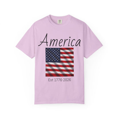 Light pink unisex t-shirt with “America” script, U.S. flag, and “Est 1776-2026”