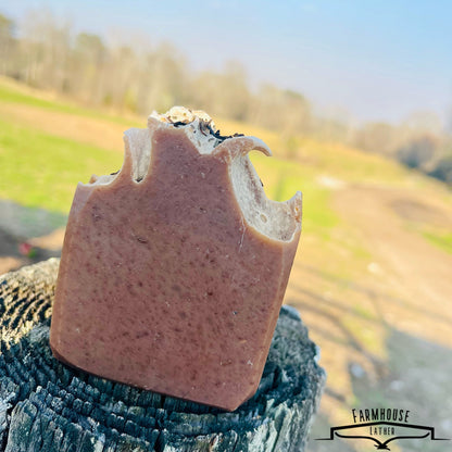 Bar soap with brown color and embedded herb flecks, upright on textured fabric