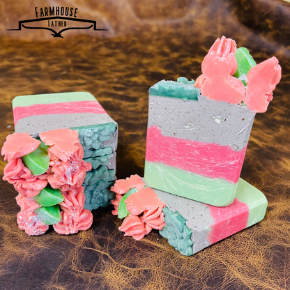 Two layered soap bars with mint-lime, pink, and speckled gray blocks and floral accents