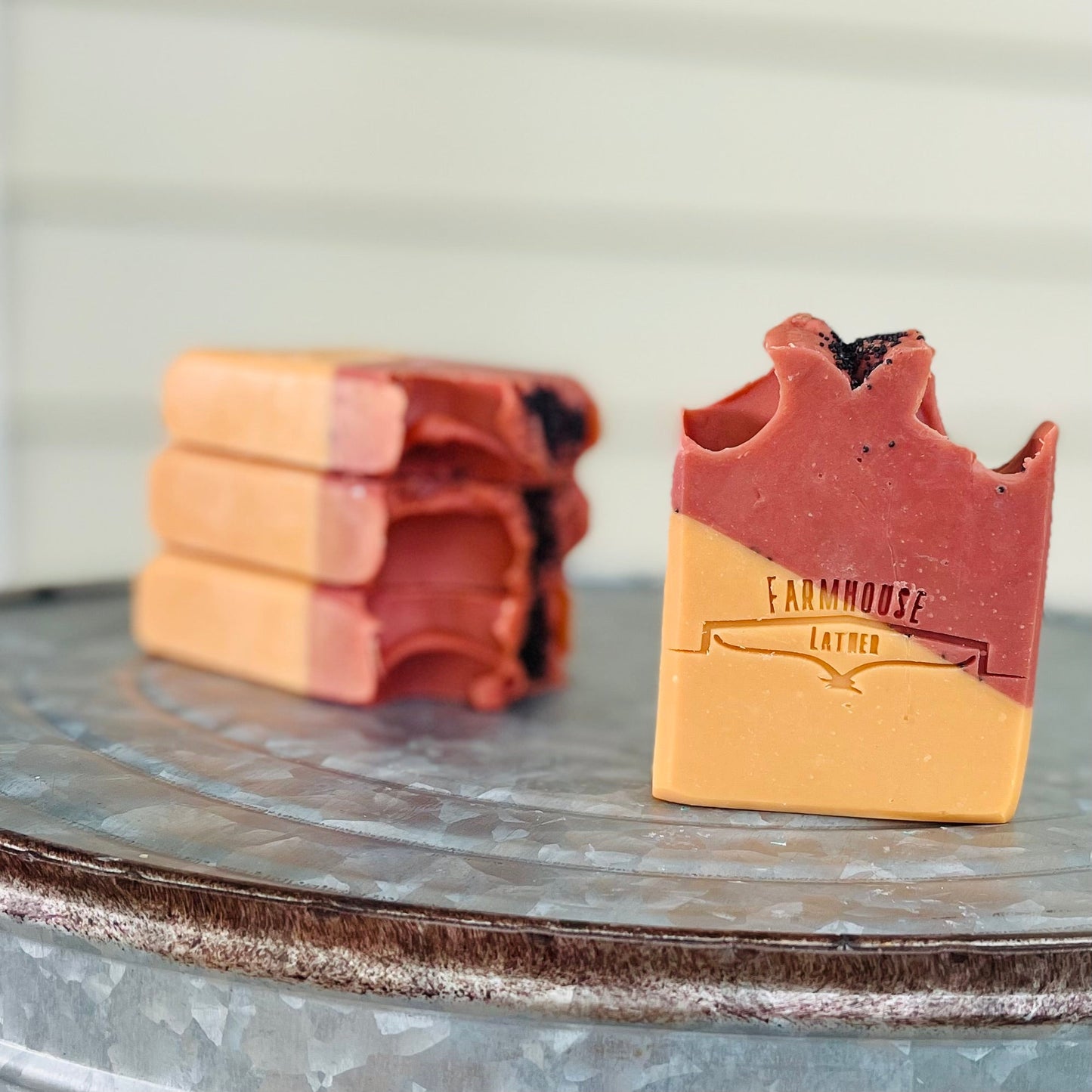Handmade soap bars: stacked red and tan bars with 'Farmhouse Lather' stamp