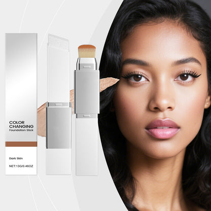 Color-changing foundation stick with brush tip in silver case, shown on dark-skin model.