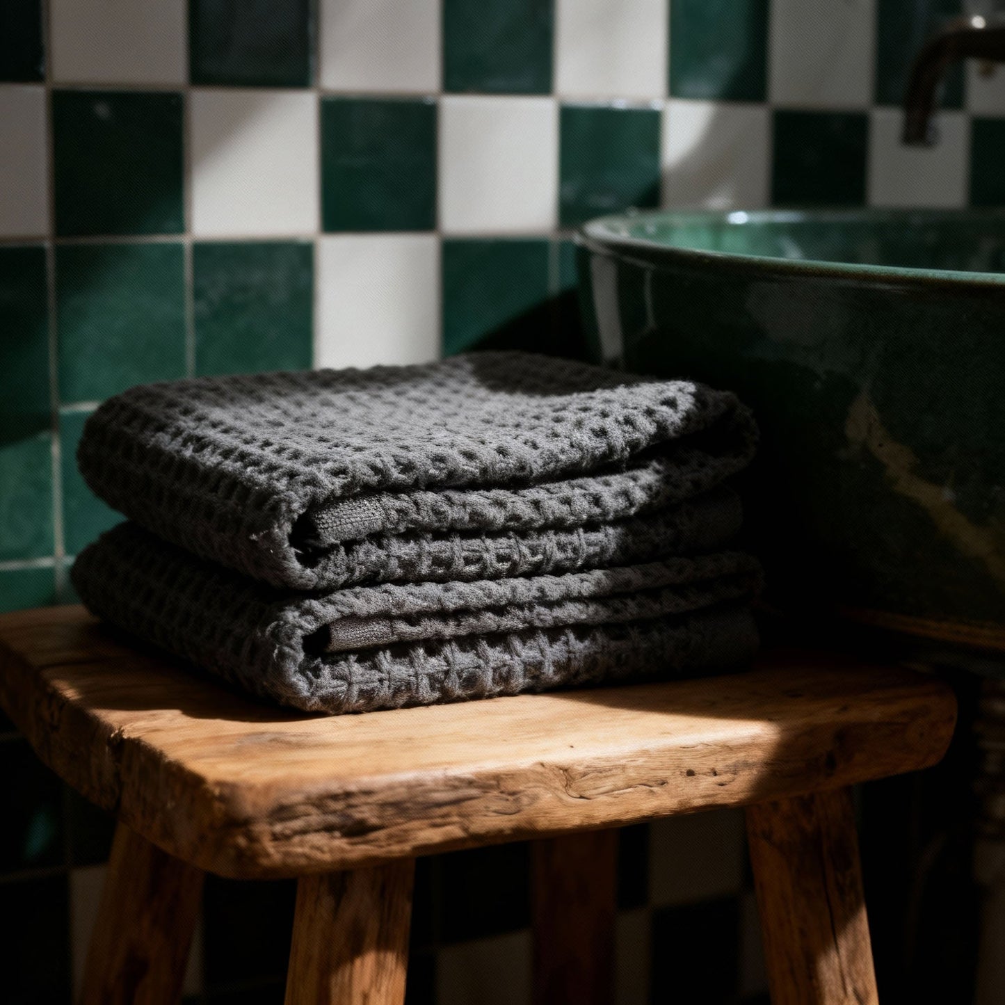 Charcoal waffle cotton towels, folded stack of 2 on a bench