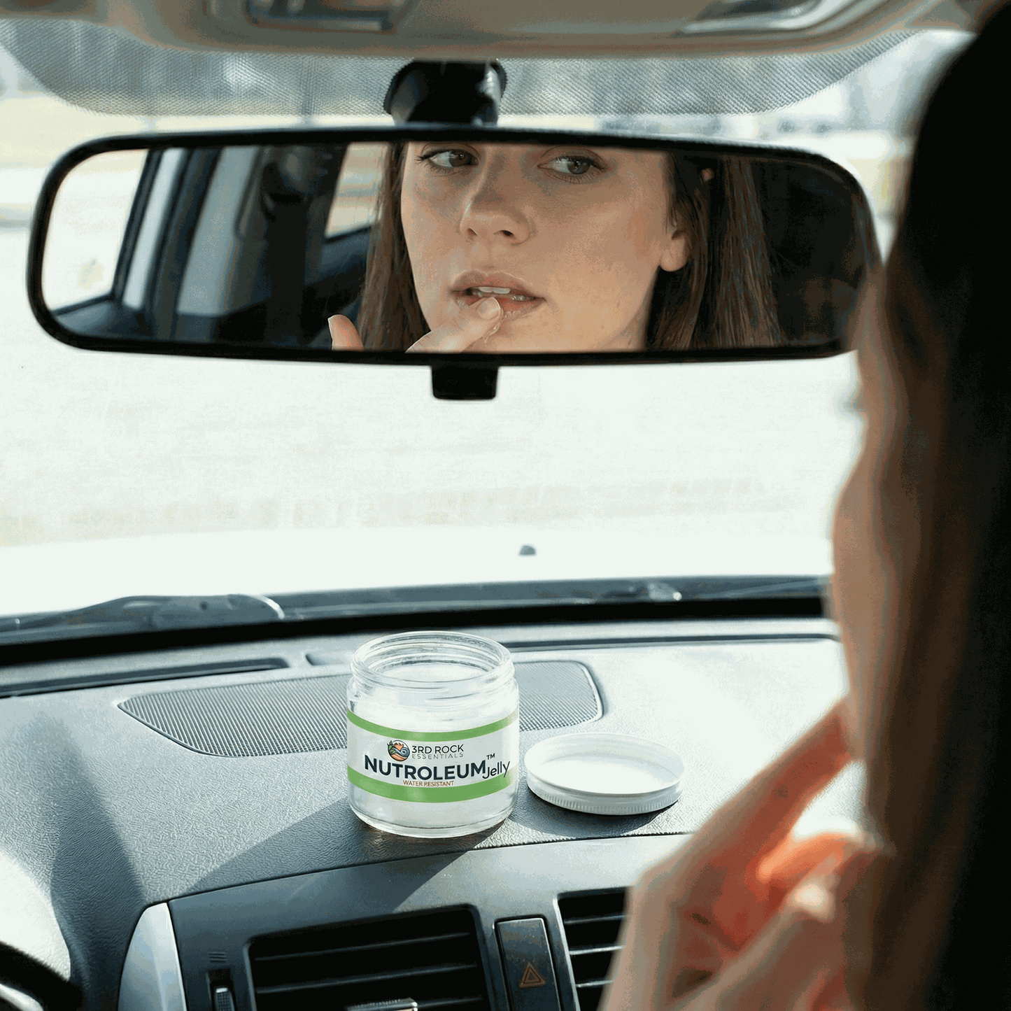 Skin balm jar on car dashboard with white lid and green label