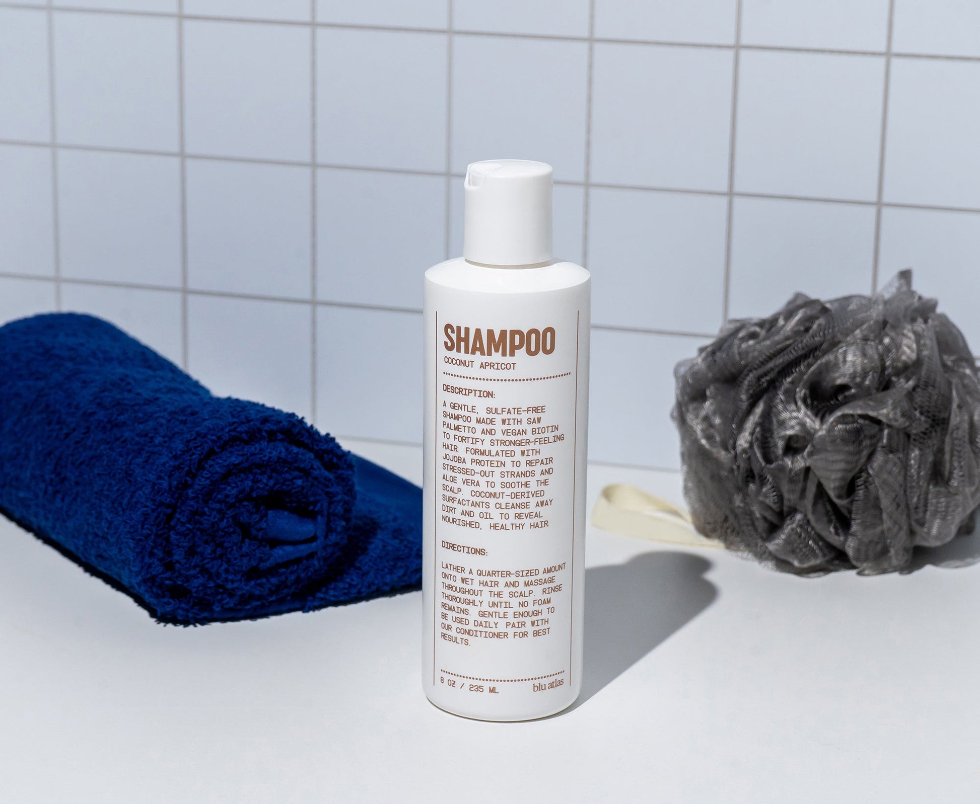 Natural shampoo bottle with SHAMPOO front label on countertop