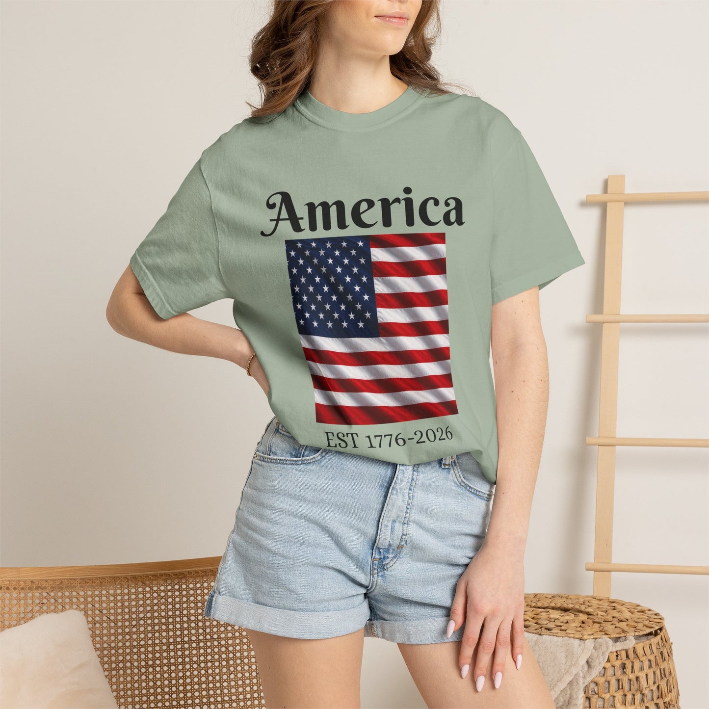 Light green T-shirt with America script, U.S. flag graphic, and EST 1776-2026 text