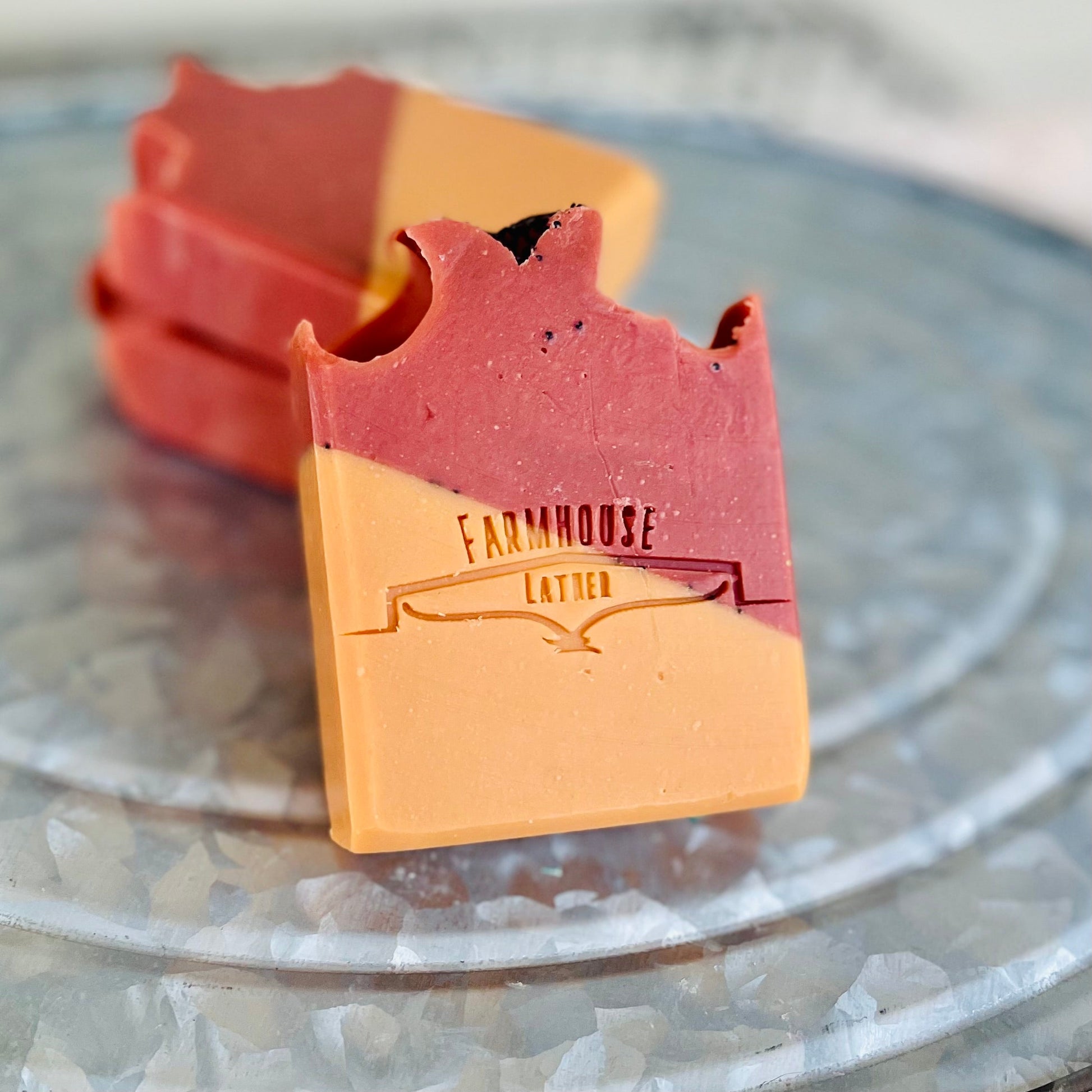 Handmade soap bar, red top and tan base, stamped 'Farmhouse Lather'
