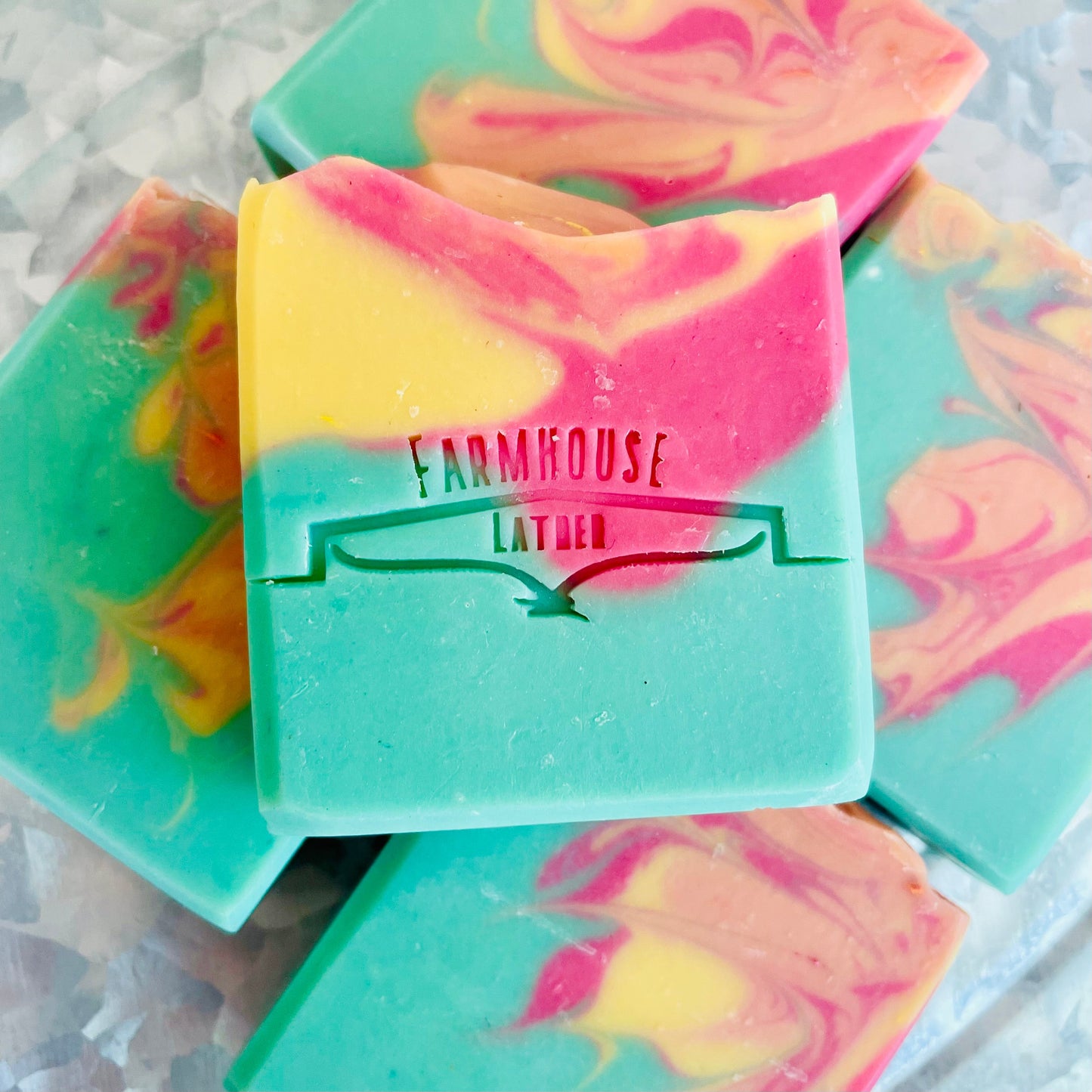 Marbled soap bar in teal, pink, and yellow with Farmhouse label on front.
